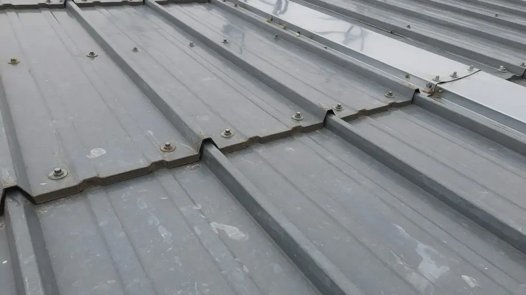 Close-up of trapezoidal metal roof sheets with fixings and overlapping end laps